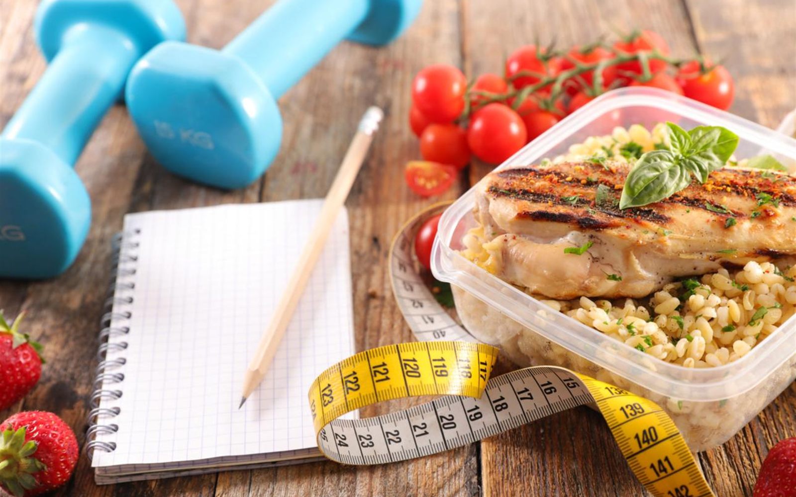 Marmita fitness com frango e grãos ao lado de acessórios de treino